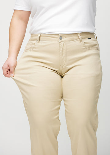 Regular-jeans til kvinner i beige, fargen Gazelles. En plus size-modell strekker stoffet ved låret for å vise stretchen.