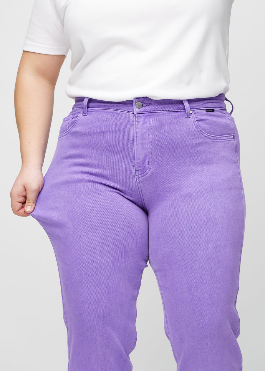 Regular-jeans til kvinner i lilla, fargen Lavenders. En plus size-modell strekker stoffet ved låret for å vise stretchen.
