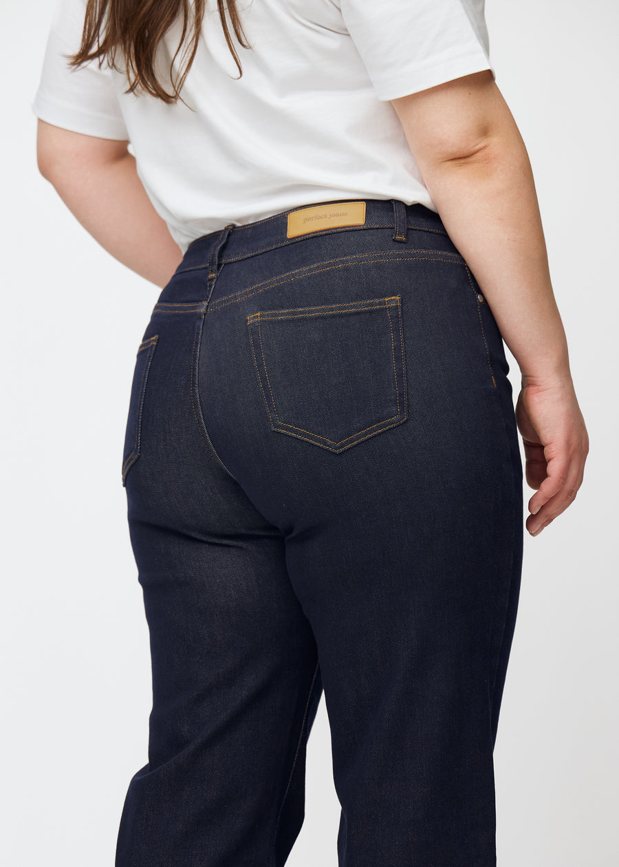 Dyp mørkeblå denim jeans til kvinner i fargen Midnights sett bakfra på nært hold på plus-size-modell.