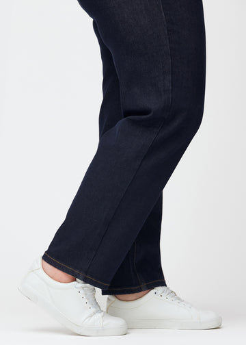 Dyp mørkeblå denim jeans til kvinner i fargen Midnights med regular passform sett på nært hold ved anklene på plus-size-modell for å vise den rette avslutningen.