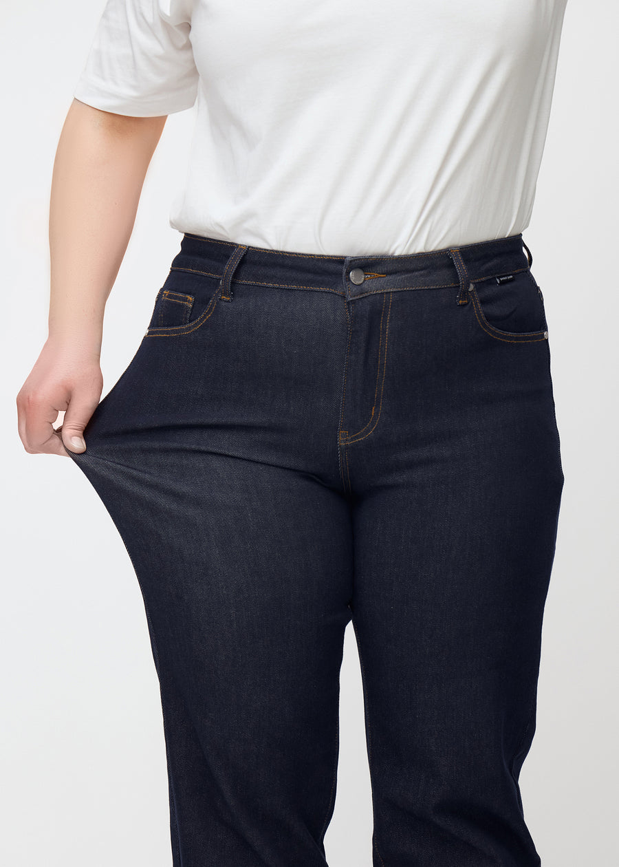 Plus-size-modell strekker dyp mørkeblå denim jeans til kvinner i fargen Midnights ved låret for å vise materialets stretch.