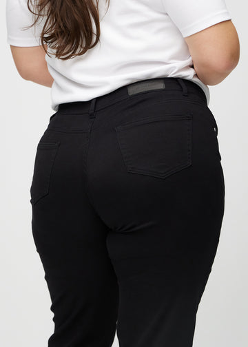 Svarte regular jeans sett bakfra på nært hold på en plus-size-modell for å vise detaljer.