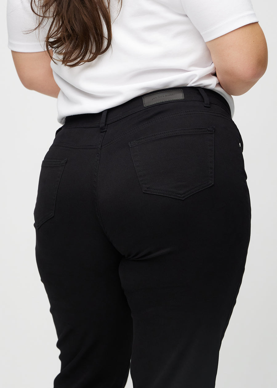 Svarte regular jeans sett bakfra på nært hold på en plus-size-modell for å vise detaljer.