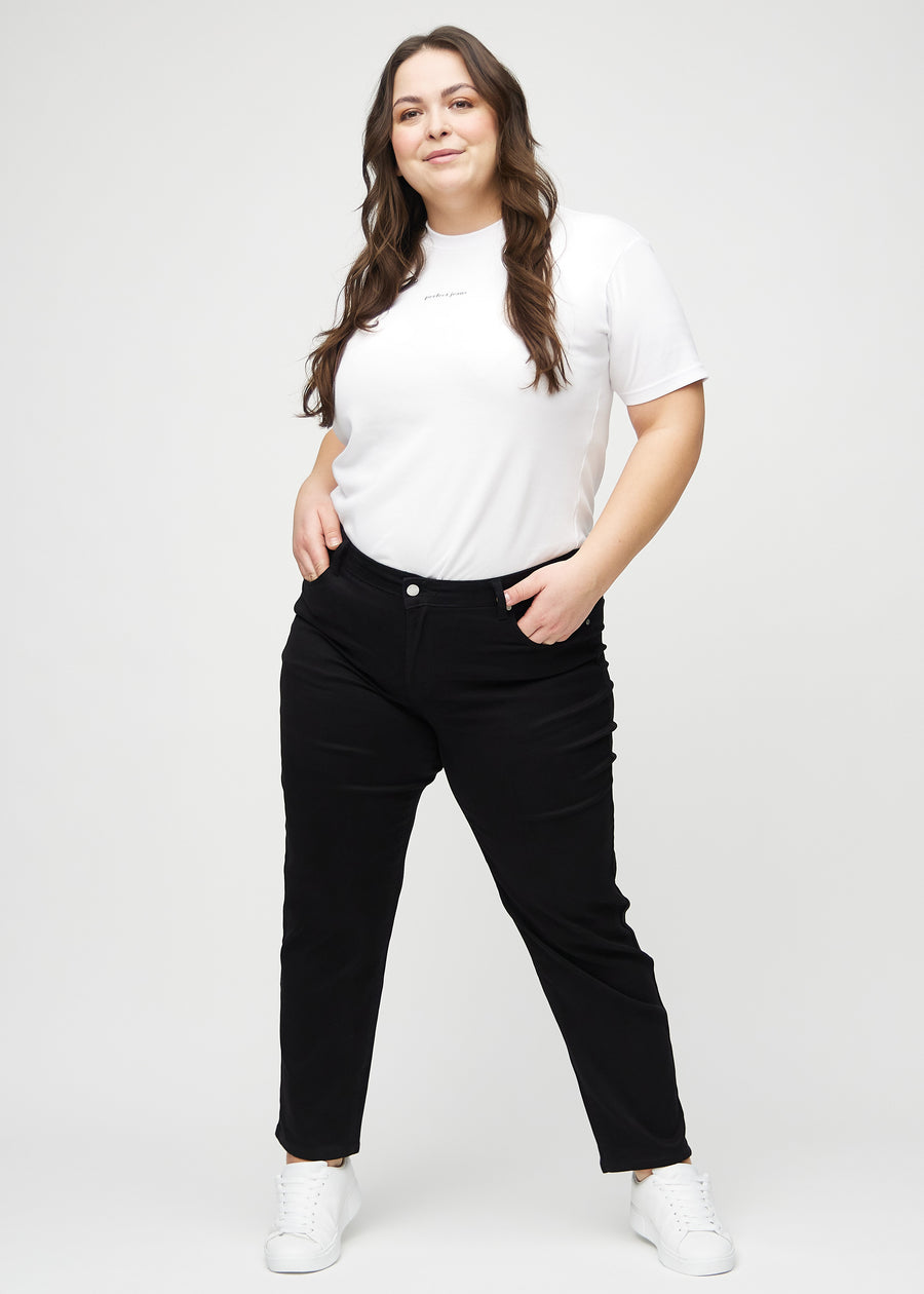 Fullt bilde av en plus-size-modell i svarte regular jeans.