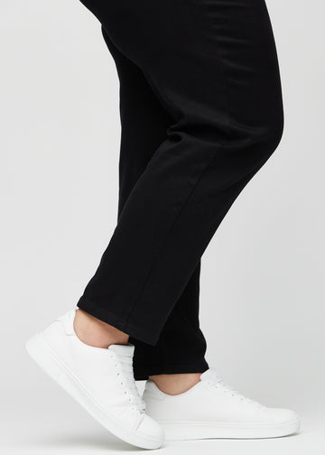 Anklene på en plus-size-modell, så man kan se hvor løst jeansene sitter i en Regular passform.