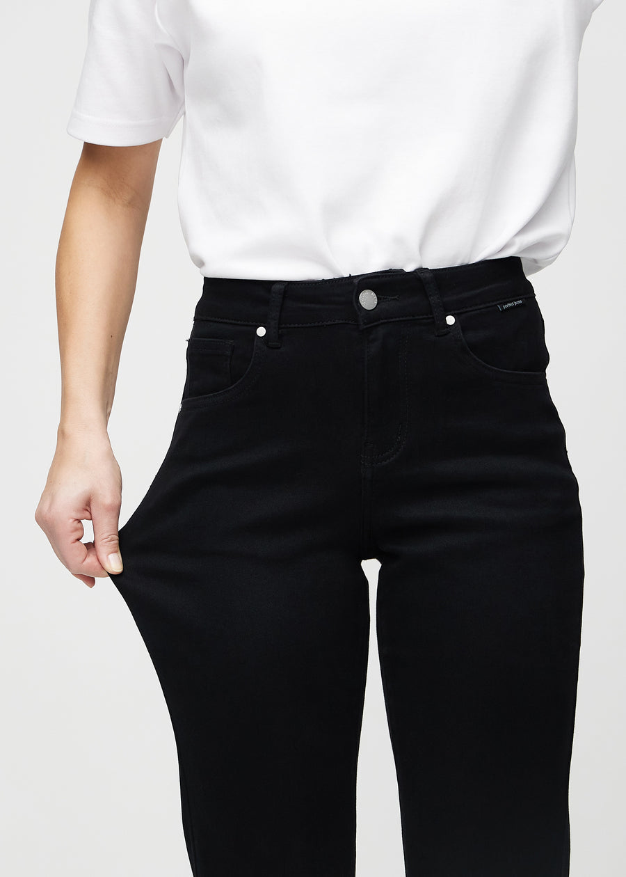 Modellen strekker jeansene ved låret for å vise stretch.
