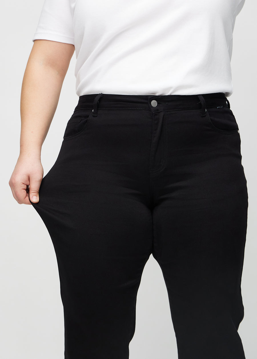 Plus-size-modellen strekker jeansene ved låret for å vise stretch.