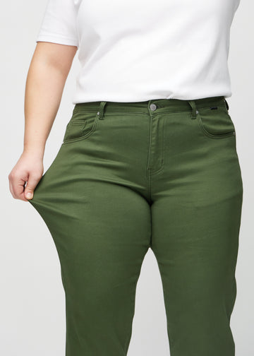 Regular-jeans til kvinner i mørkegrønn, fargen Renewals. En plus size-modell strekker stoffet ved låret for å vise stretchen.
