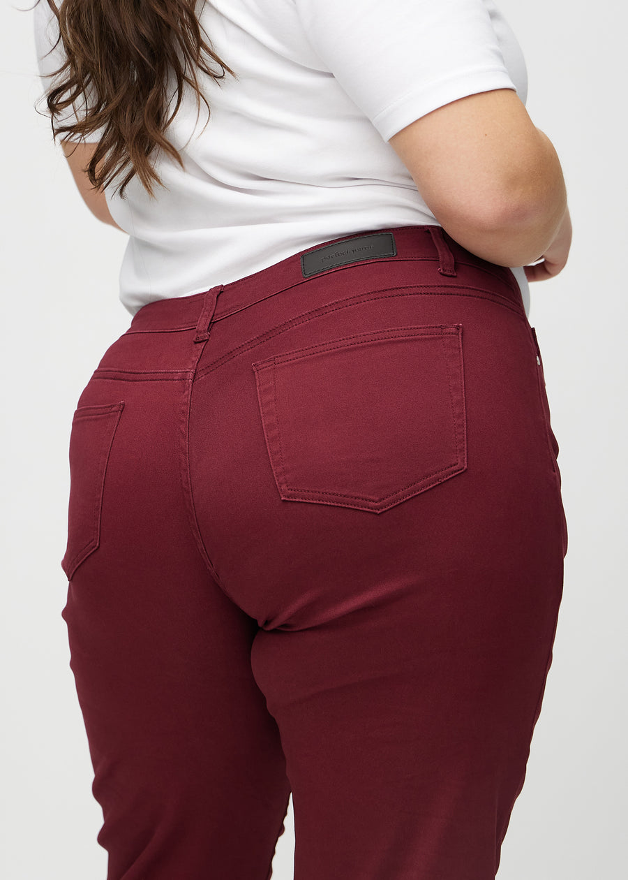 Regular-jeans til kvinner i mørkerød, fargen Santas. Nærbilde bakfra på en plus size-modell, som viser passform og detaljer.