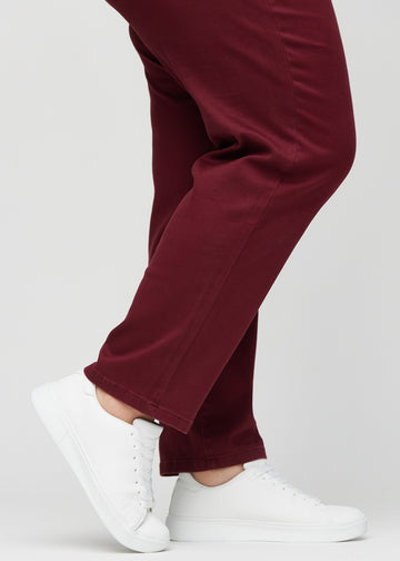 Regular-jeans til kvinner i mørkerød, fargen Santas. Nærbilde ved anklene på en plus size-modell, som viser de rette benavslutningene.