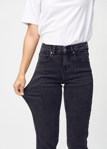 Regular-jeans til kvinner i mørkegrå, fargen Shadows. En modell strekker stoffet ved låret for å vise stretchen.