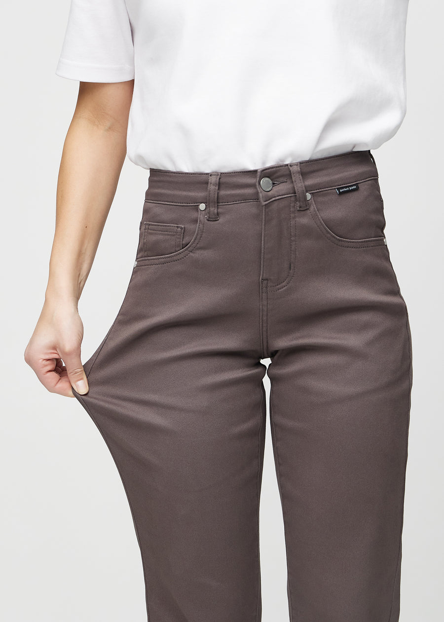 Regular-jeans til kvinner i gråbrun, fargen Thunders. En modell strekker stoffet ved låret for å vise stretchen.