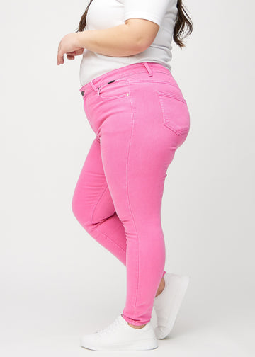 Skinny-jeans til kvinner i lyserosa, fargen Flamingos. Sett fra siden på en plus size-modell.