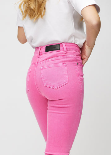 Skinny-jeans til kvinner i lyserosa, fargen Flamingos. Nærbilde bakfra på en modell for å vise detaljer.