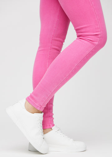 Skinny-jeans til kvinner i lyserosa, fargen Flamingos. Nærbilde ved anklene på en modell, som viser de tettsittende benåpningene.