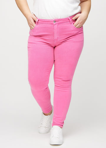 Skinny-jeans til kvinner i lyserosa, fargen Flamingos. Sett forfra på en plus size-modell, med tettsittende ben.