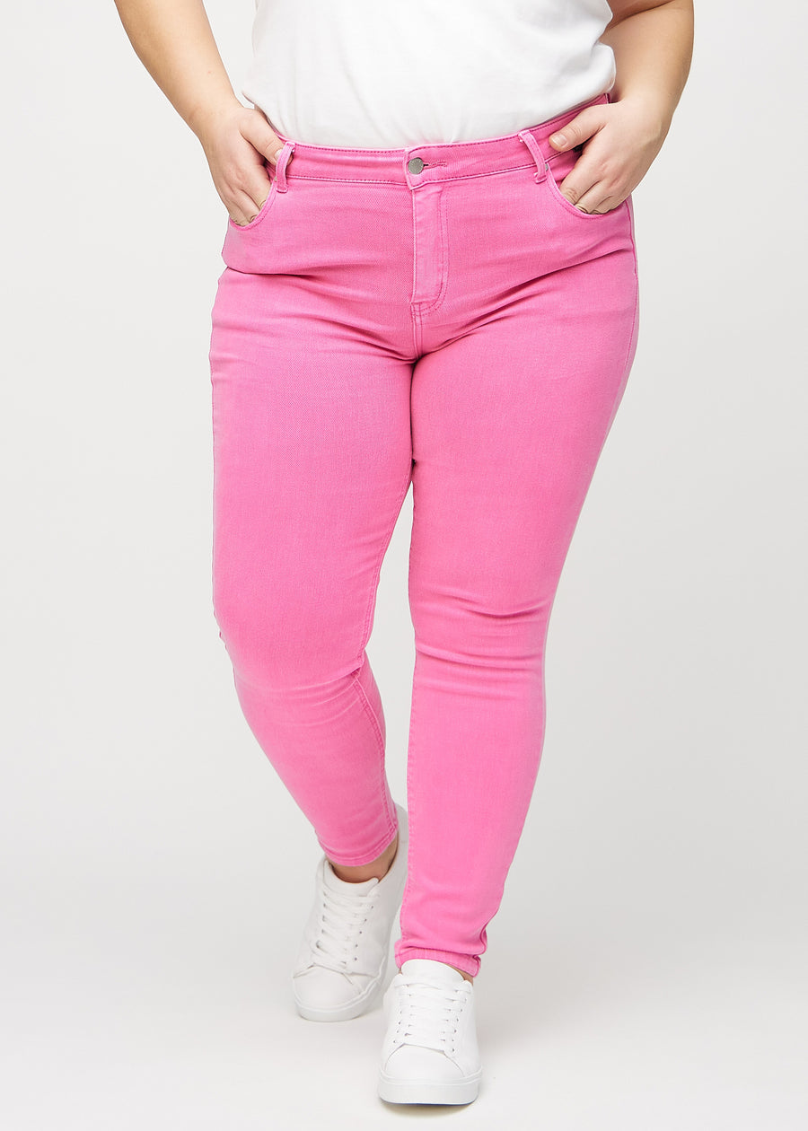 Skinny-jeans til kvinner i lyserosa, fargen Flamingos. Sett forfra på en plus size-modell, med tettsittende ben.