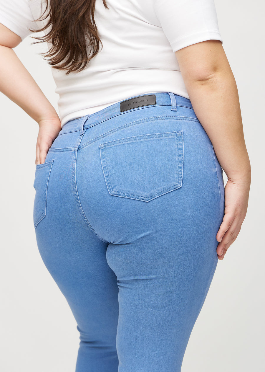 Skinny-jeans til kvinner i blå, fargen Geraniums. Nærbilde bakfra på en plus size-modell for å vise detaljene.