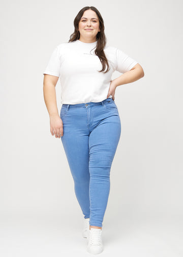 Skinny-jeans til kvinner i blå, fargen Geraniums. Helhetsbilde av en plus size-modell med jeansene på.