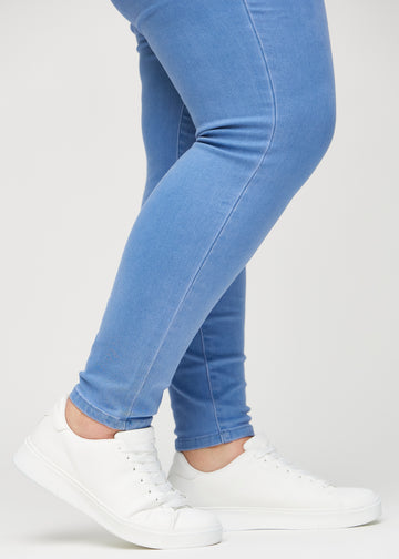 Skinny-jeans til kvinner i blå, fargen Geraniums. Nærbilde ved anklene på en plus size-modell, som viser de tettsittende benåpningene.