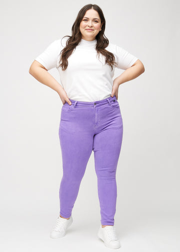 Skinny-jeans til kvinner i lilla, fargen Lavenders. Helhetsbilde av en plus size-modell med jeansene på.