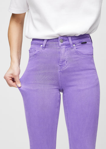 Skinny-jeans til kvinner i lilla, fargen Lavenders. En modell strekker jeansstoffet ved låret for å vise stretchen.