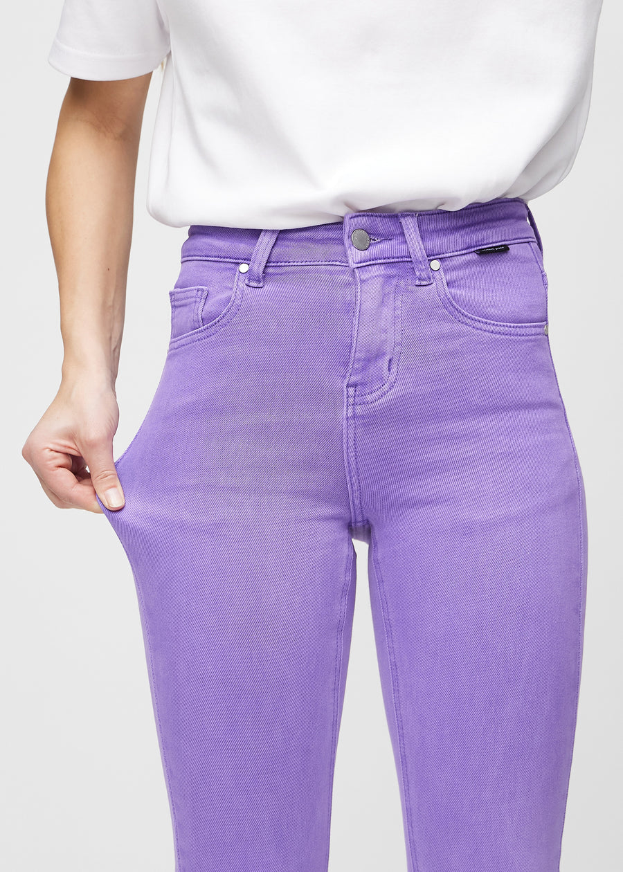 Skinny-jeans til kvinner i lilla, fargen Lavenders. En modell strekker jeansstoffet ved låret for å vise stretchen.