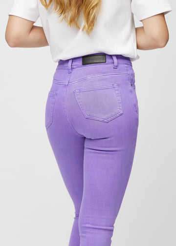 Skinny-jeans til kvinner i lilla, fargen Lavenders. Nærbilde bakfra på en modell for å vise detaljer.