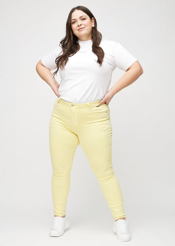 Skinny-jeans til kvinner i lysegul, fargen Lemonades. Helhetsbilde av en plus size-modell med jeansene på.