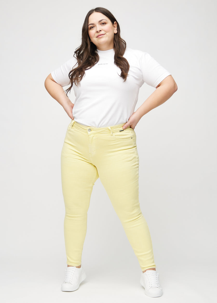 Skinny-jeans til kvinner i lysegul, fargen Lemonades. Helhetsbilde av en plus size-modell med jeansene på.