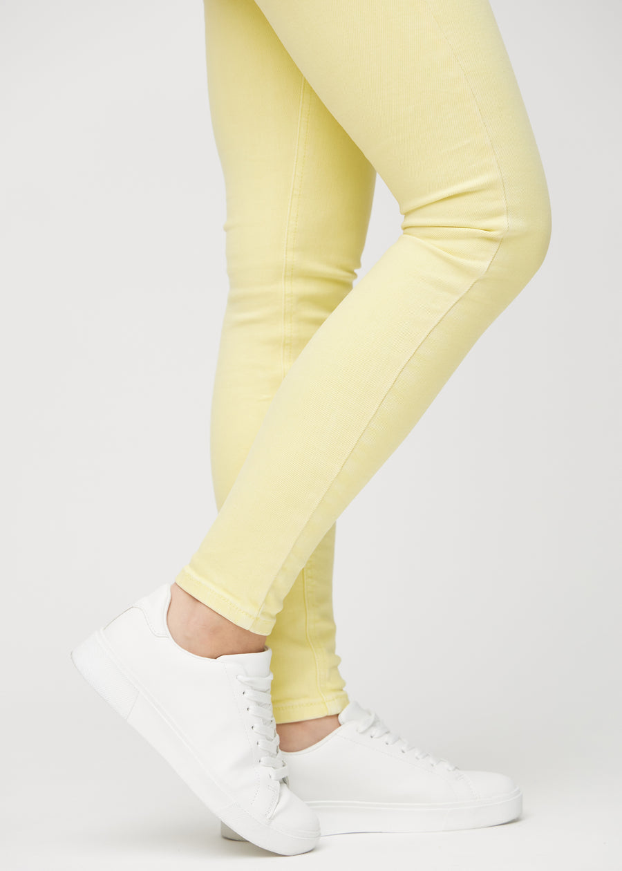 Skinny-jeans til kvinner i lysegul, fargen Lemonades. Nærbilde ved anklene på en modell, som viser de tettsittende benåpningene.