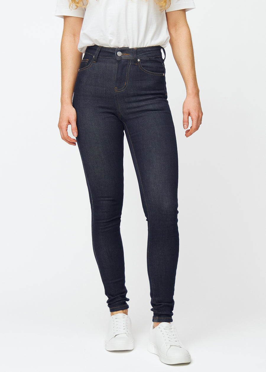 Dyp mørkeblå denim jeans til kvinner i fargen Midnights med skinny passform, som sitter tett fra midje til ankel, sett forfra.