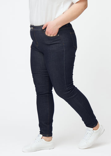 Dyp mørkeblå denim jeans til kvinner i fargen Midnights med skinny passform sett fra siden på plus-size-modell.
