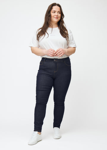Fullt bilde av plus-size-modell i dyp mørkeblå denim jeans til kvinner i fargen Midnights med skinny passform.