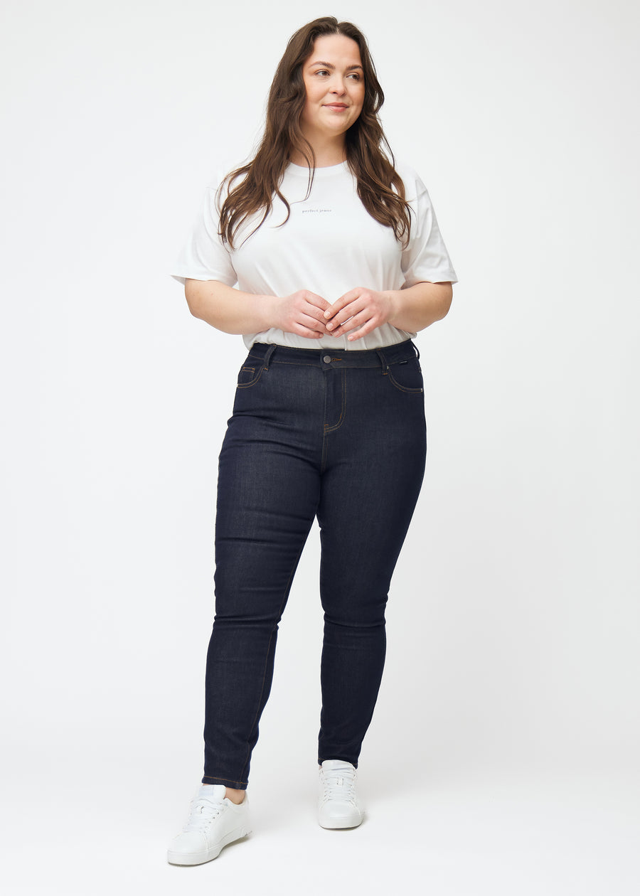 Fullt bilde av plus-size-modell i dyp mørkeblå denim jeans til kvinner i fargen Midnights med skinny passform.