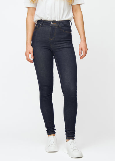 Dyp mørkeblå denim jeans til kvinner i fargen Midnights med skinny passform, som sitter tett fra midje til ankel, sett forfra.