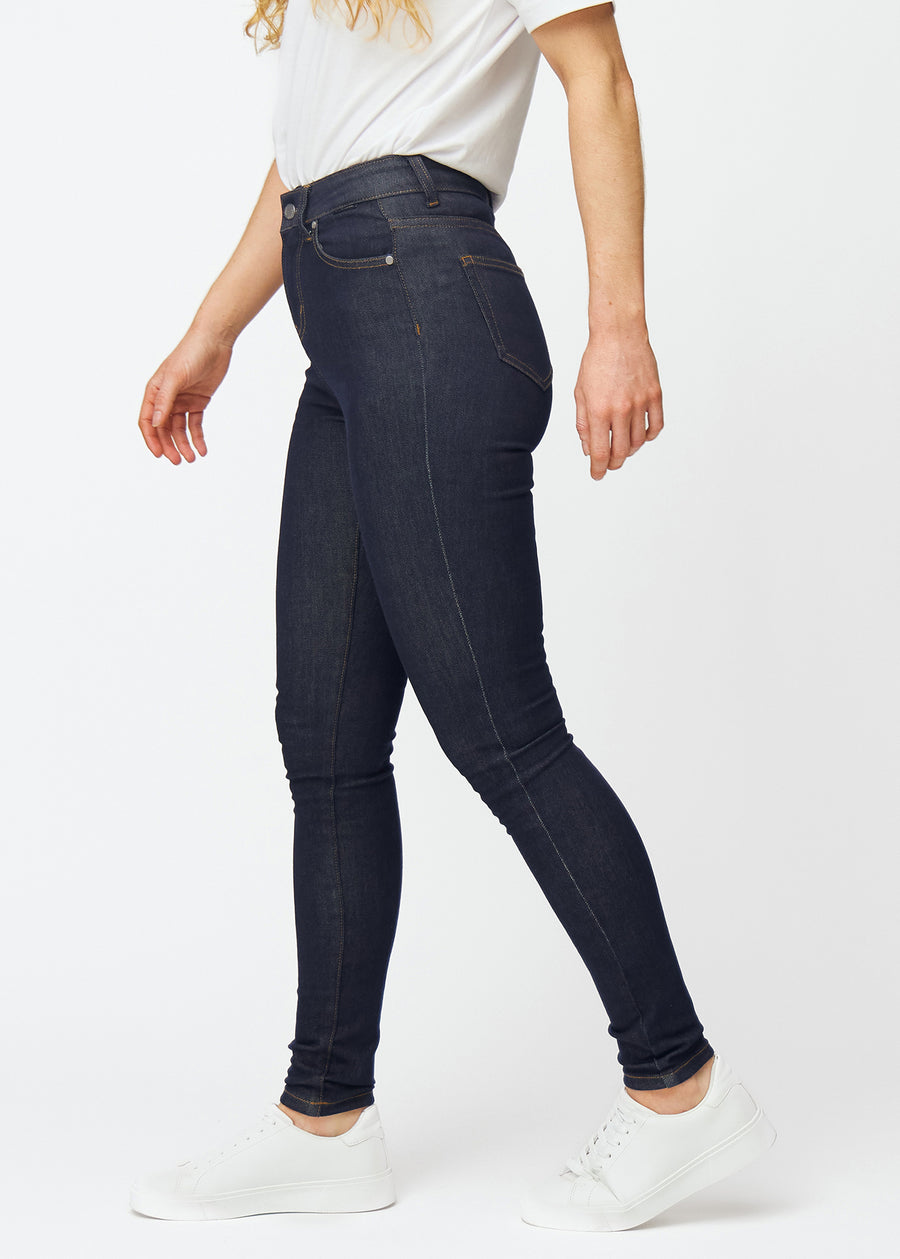 Dyp mørkeblå denim jeans til kvinner i fargen Midnights med skinny passform sett fra siden på modell.