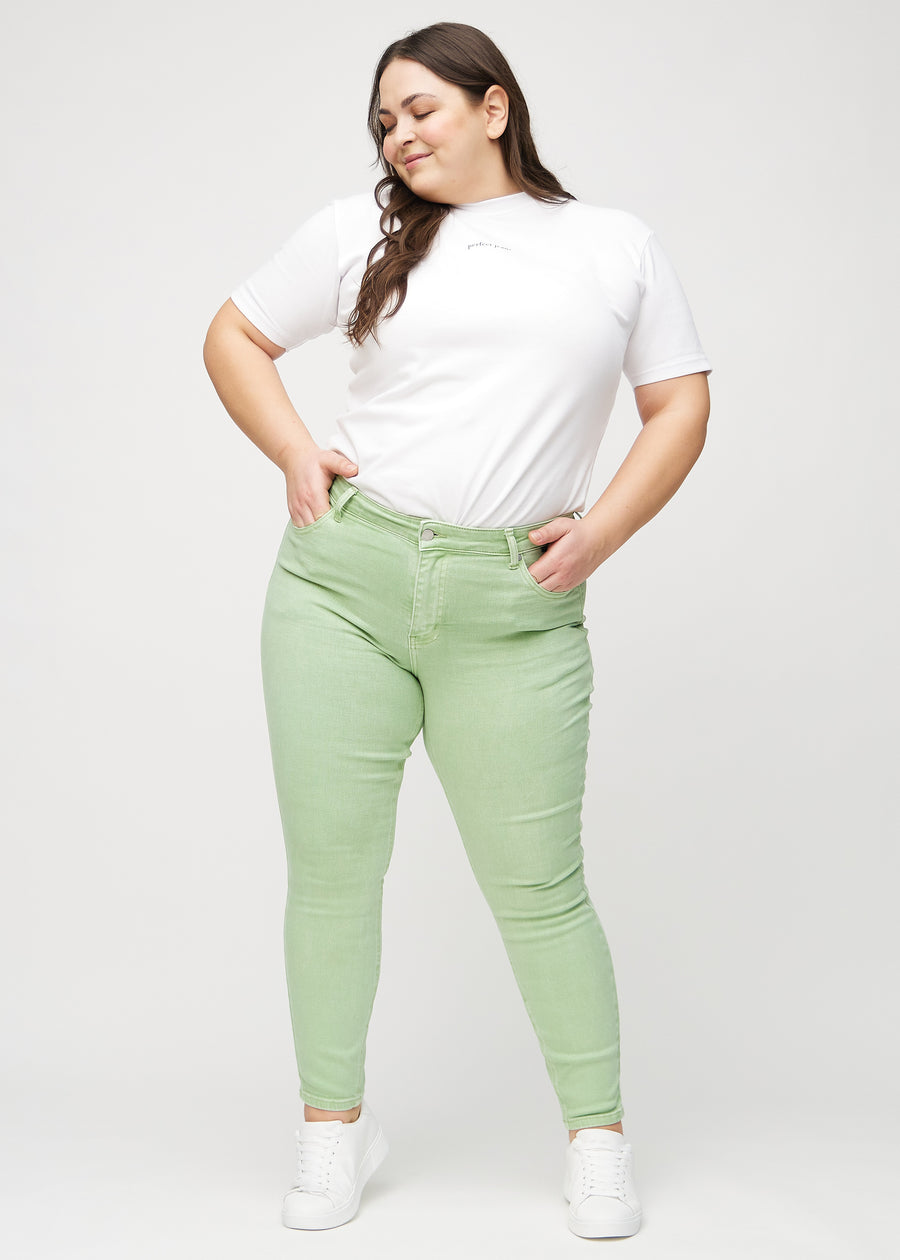 Skinny-jeans til kvinner i lysegrønn, fargen Mints. Helhetsbilde av en plus size-modell med jeansene på.