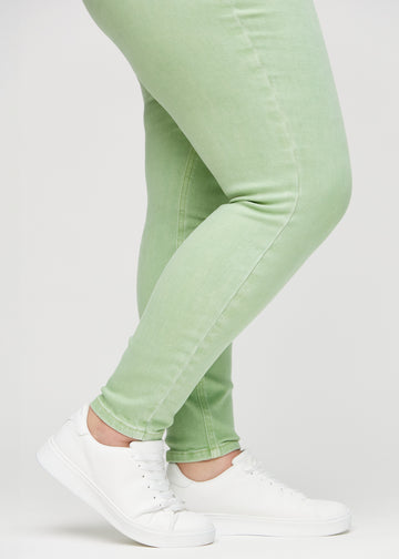 Skinny-jeans til kvinner i lysegrønn, fargen Mints. Nærbilde ved anklene på en plus size-modell, som viser de tettsittende benåpningene.
