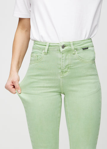 Skinny-jeans til kvinner i lysegrønn, fargen Mints. En modell strekker jeansstoffet ved låret for å vise stretchen.