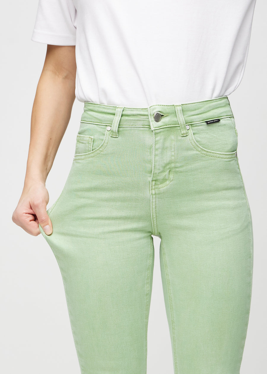 Skinny-jeans til kvinner i lysegrønn, fargen Mints. En modell strekker jeansstoffet ved låret for å vise stretchen.