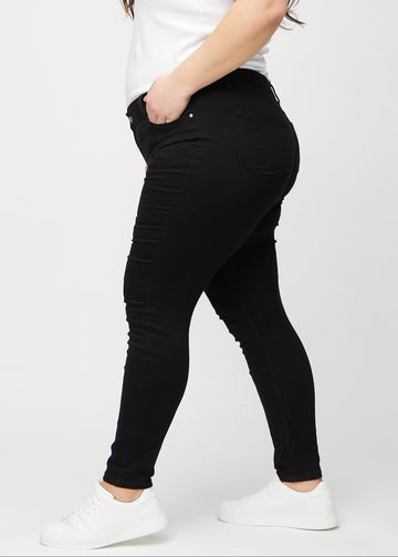 Svarte skinny jeans sett fra siden på en plus-size-modell.