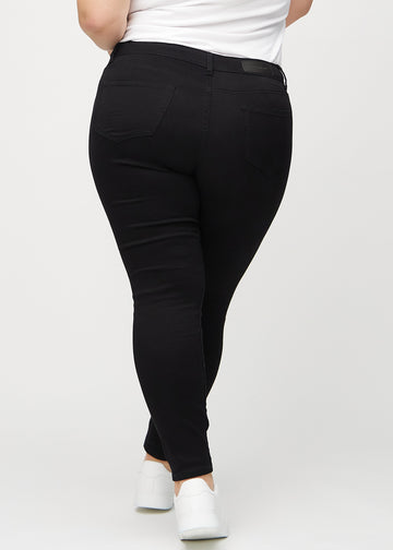 Svarte skinny jeans sett bakfra på en plus-size-modell, så man kan se hele produktet.