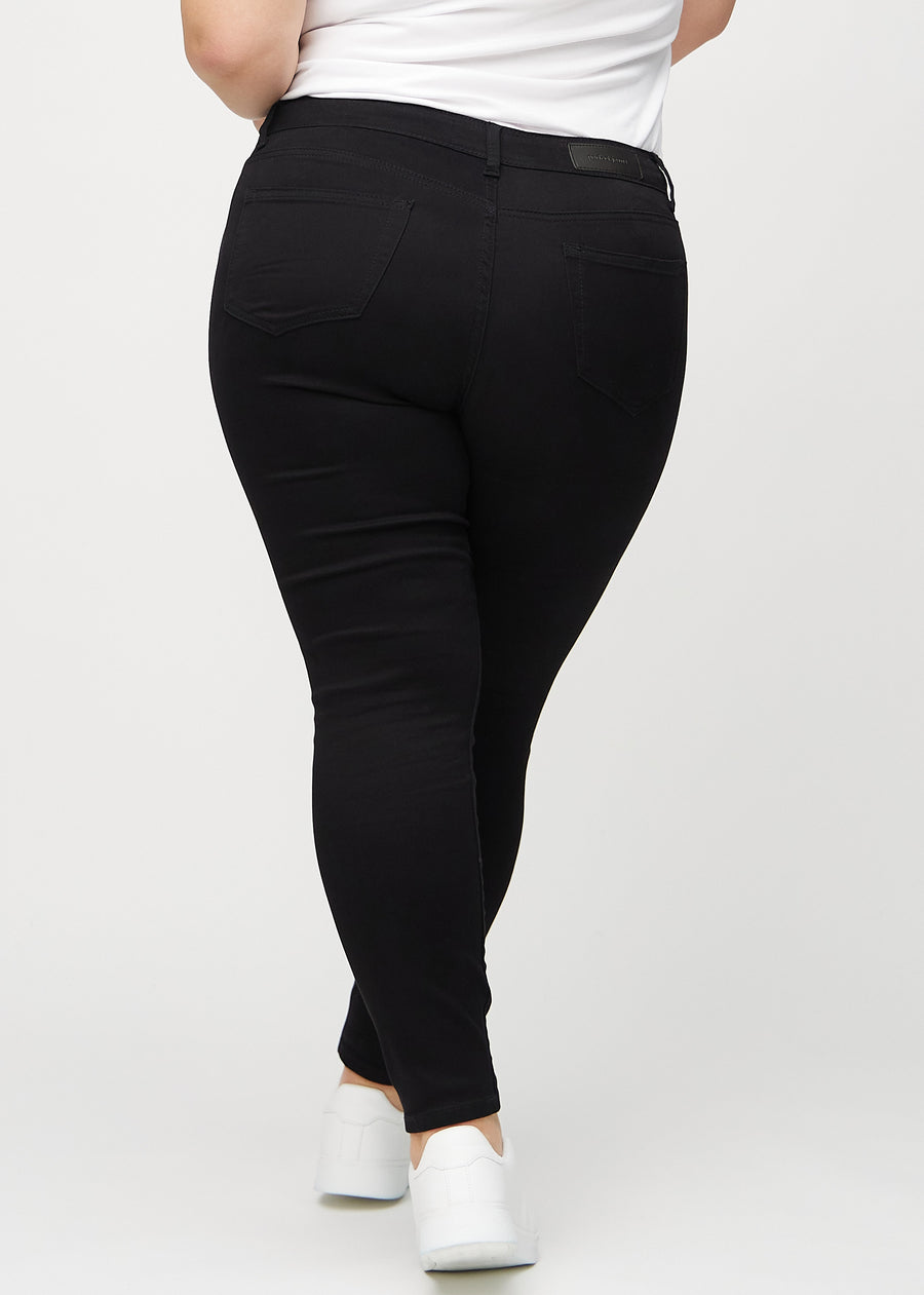 Svarte skinny jeans sett bakfra på en plus-size-modell, så man kan se hele produktet.