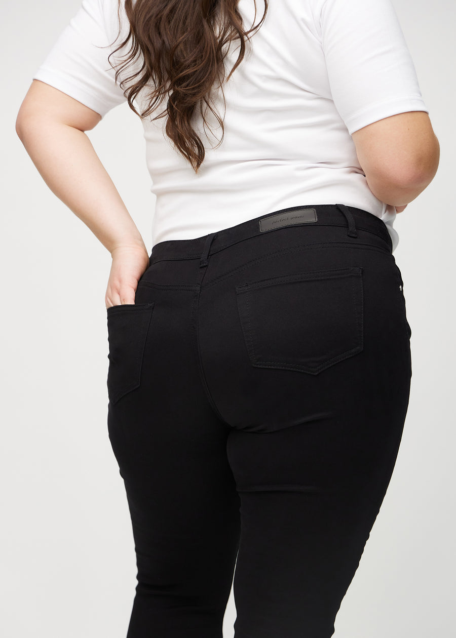 Svarte skinny jeans sett bakfra på nært hold på en plus-size-modell for å vise detaljer.