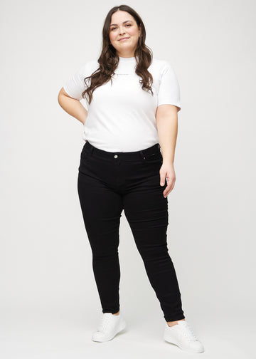 Fullt bilde av en plus-size-modell i svarte skinny jeans.