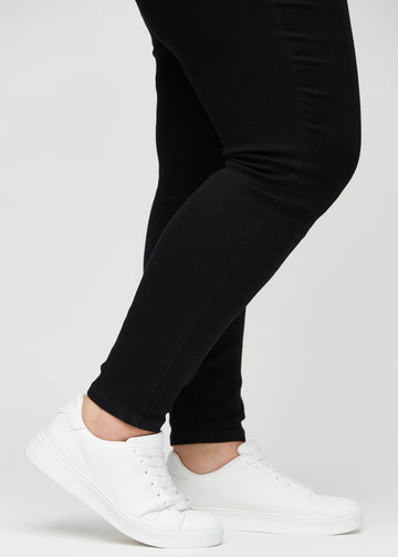 Anklene på en plus-size-modell, så man kan se hvor tett jeansene sitter i en Skinny passform.