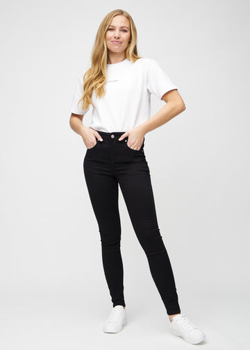 Fullt bilde av modell i svarte skinny jeans.