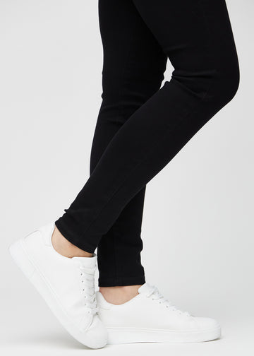 Anklene på en modell, så man kan se hvor tett jeansene sitter i en Skinny passform.
