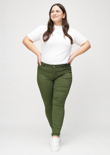 Skinny-jeans til kvinner i mørkegrønn, fargen Renewals. Helhetsbilde av en plus size-modell med jeansene på.